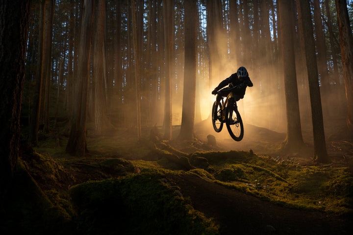 The new Trek Fuel EXE with rider jumping through the forest. Silhouette with misty  sunburnt backgrounf