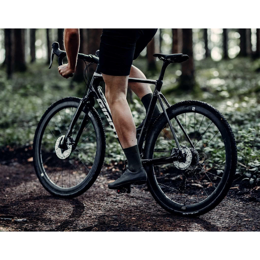 Man riding a bike wearing black gravel cycling shoes